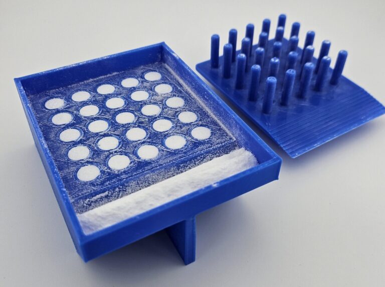 That excess is then swept into the basin, leaving the holes filled with uniformly compressed powder